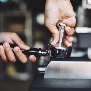 Bar Cafetería en Montanejos - Los Luises. Close-up of a barista tamping coffee grounds using an espresso tamper.