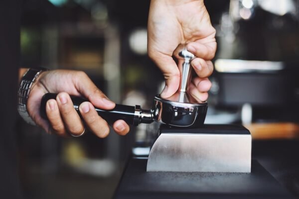 Bar Cafetería en Montanejos - Los Luises. Close-up of a barista tamping coffee grounds using an espresso tamper.